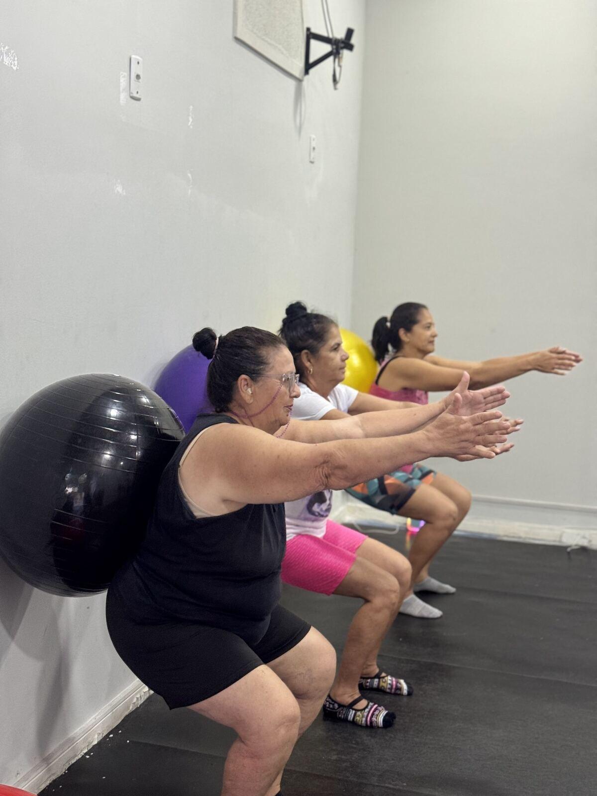 Alunas de Pilates fazendo agachamento com a bola apoiada na parede