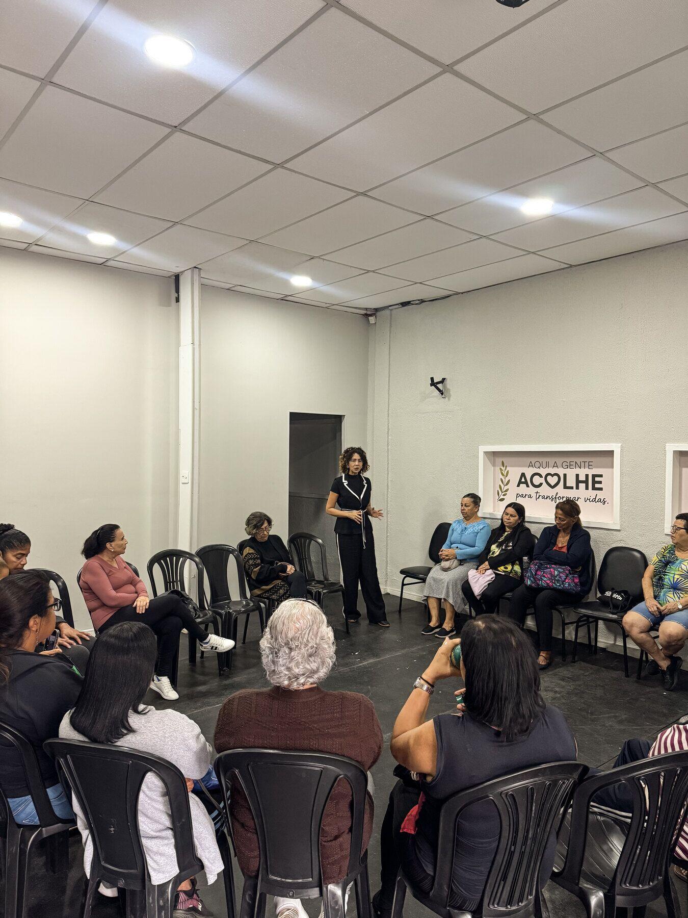 Roda de conversa no salão do Instituto, com as pessoas sentadas em cadeiras e uma palestrante em pé